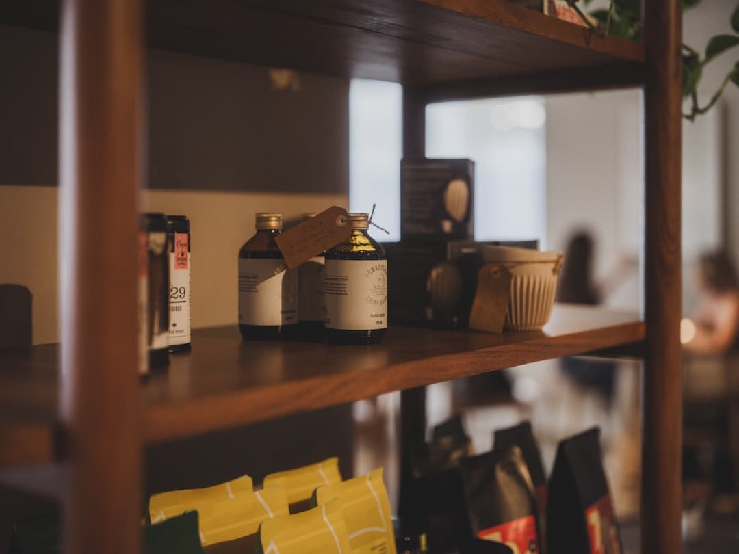 Labelled glass bottles lined up on a wooden shelf in warm daylight