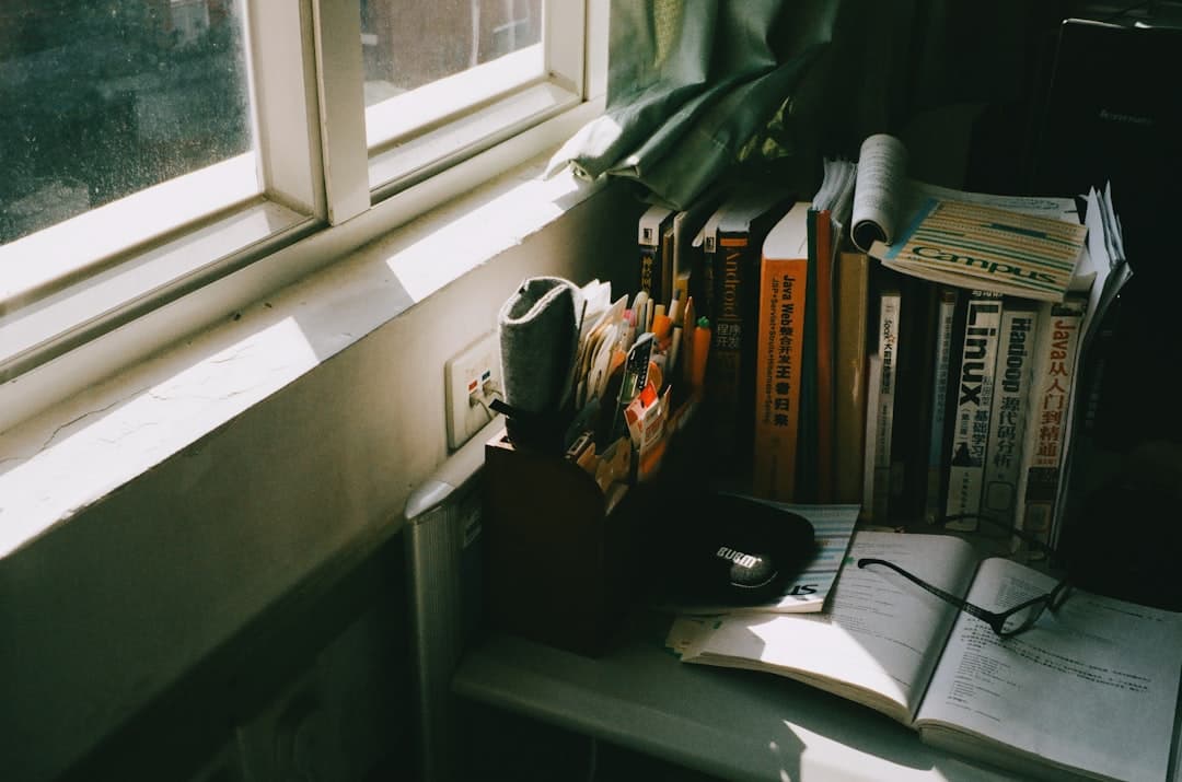 Books and glasses on a wooden table by a sunlit window in soft daylight