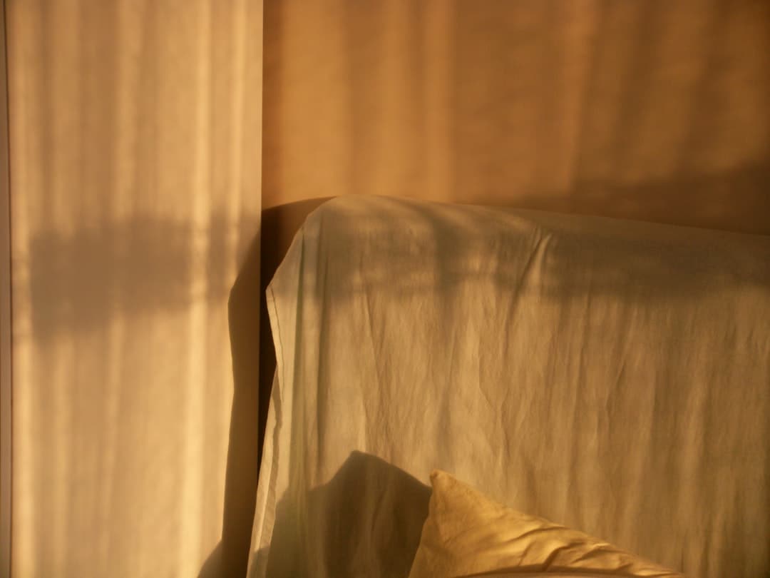 Warm morning light and soft shadows falling across draped linen bedding