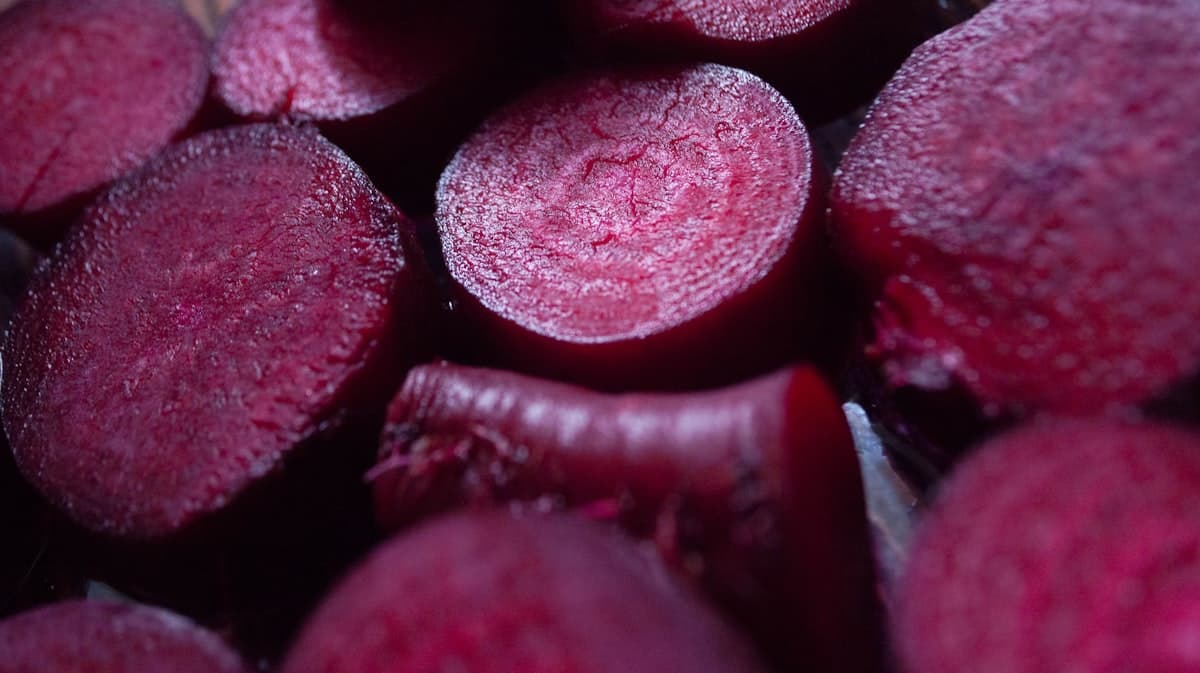 Freshly cut red beets displayed on a dark surface, showing the deep magenta interior of sliced beet rounds