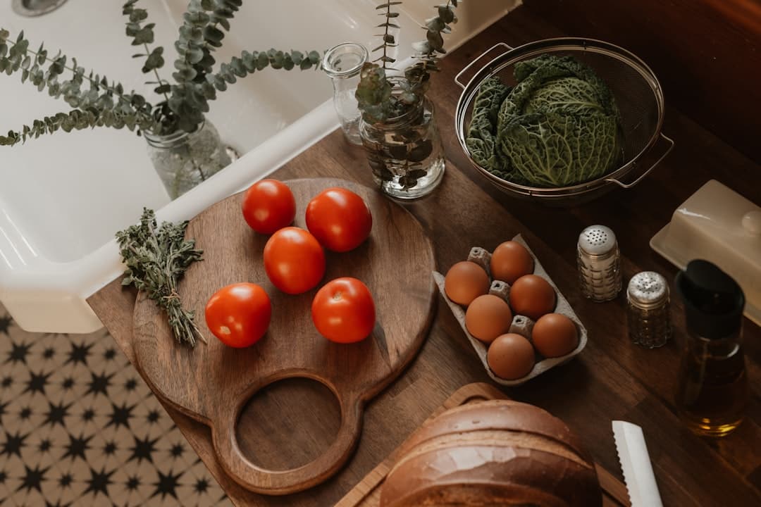 Fresh tomatoes on a wooden board, brown eggs, and savoy cabbage on a rustic kitchen counter