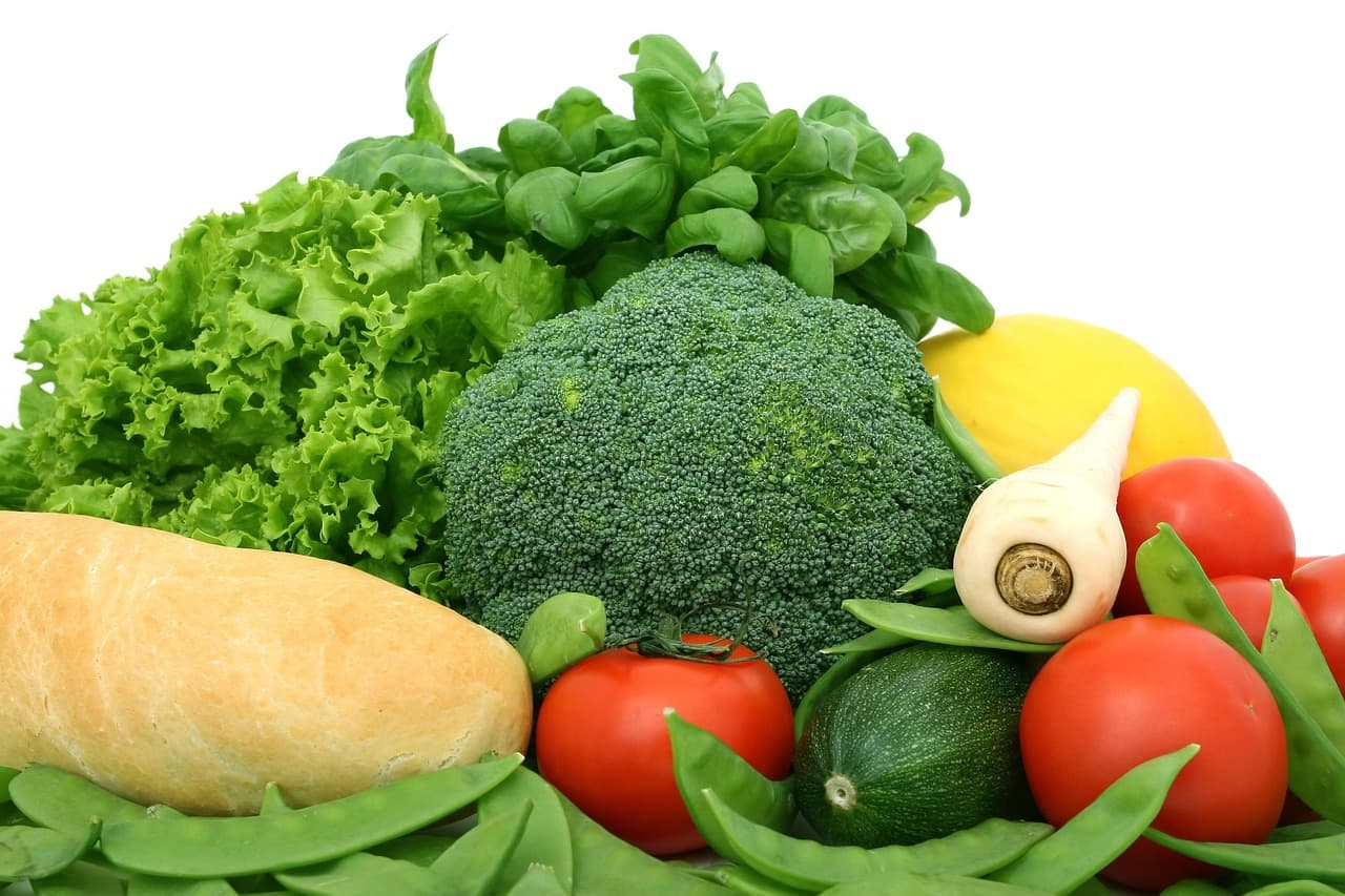 Fresh broccoli, lettuce and other whole vegetables arranged on a light surface in daylight