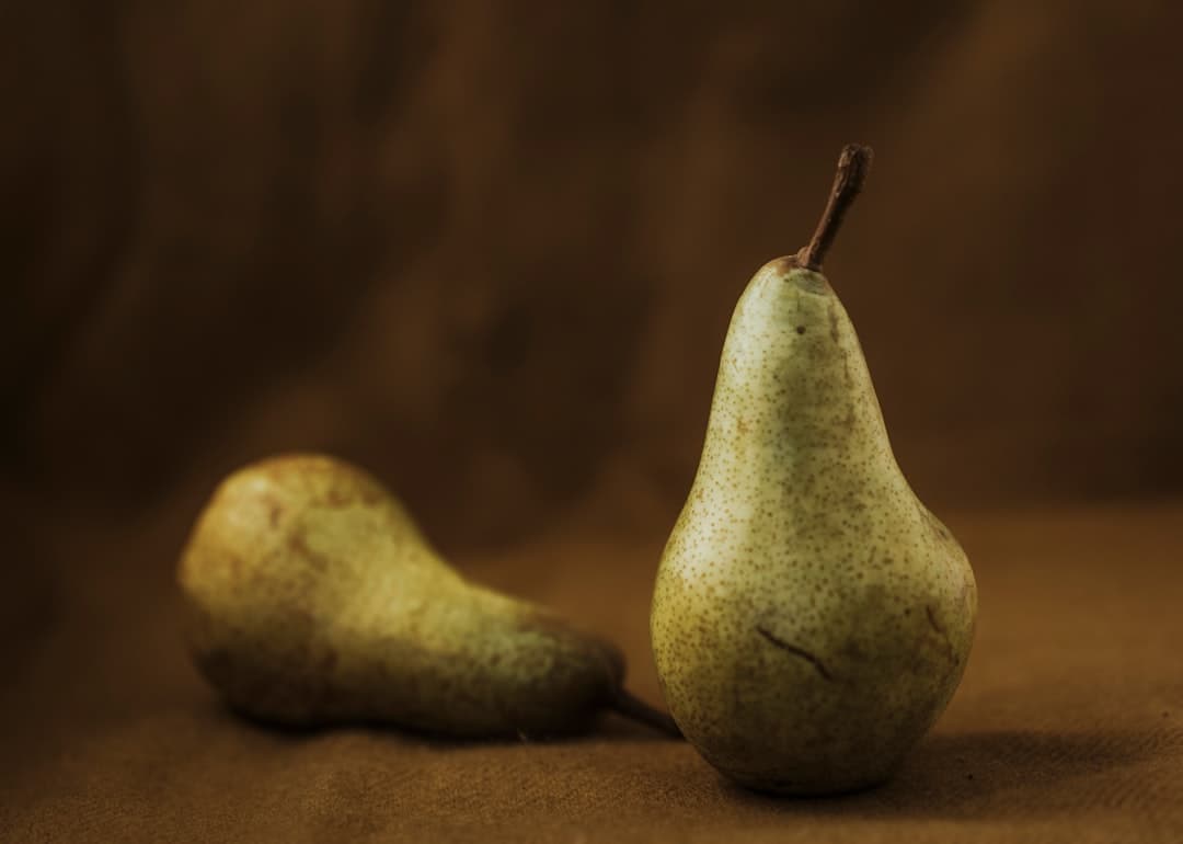 Ripe pears resting on a brown wooden table in soft daylight