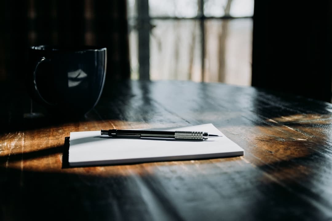 A pen resting on an open notebook on a wooden table